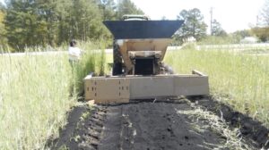 A tractor spreads biochar in a field.